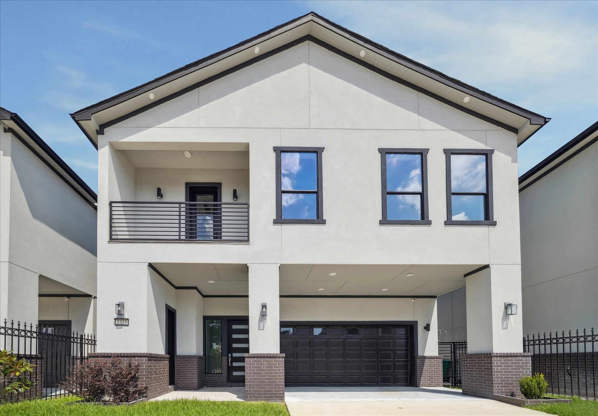 Modern design defines this gated residence, with a streamlined façade and crisp architectural lines. A private driveway and attached garage add ease and seclusion, while the second-level balcony and tall windows fill the interiors with natural light.