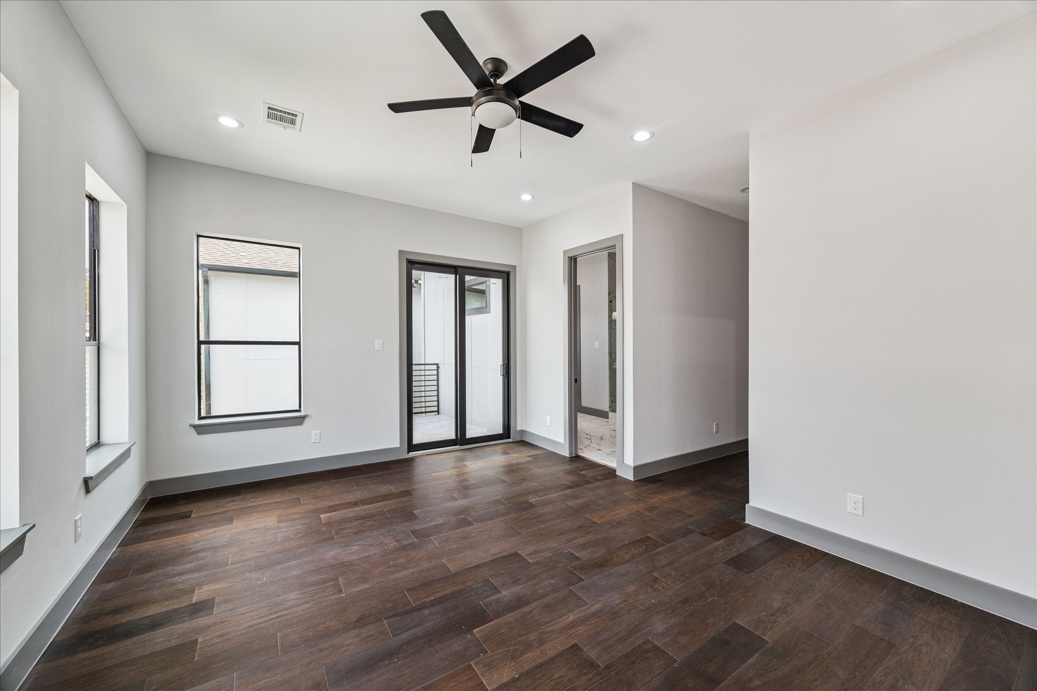 2323 Tuam Street Houston, TX 77004 - Photo 14 of 24 In the primary suite, elegant wood floors, recessed lighting, and a ceiling fan create comfort, while a sliding glass door opens to a private balcony and provides seamless entry to the en suite bathroom.