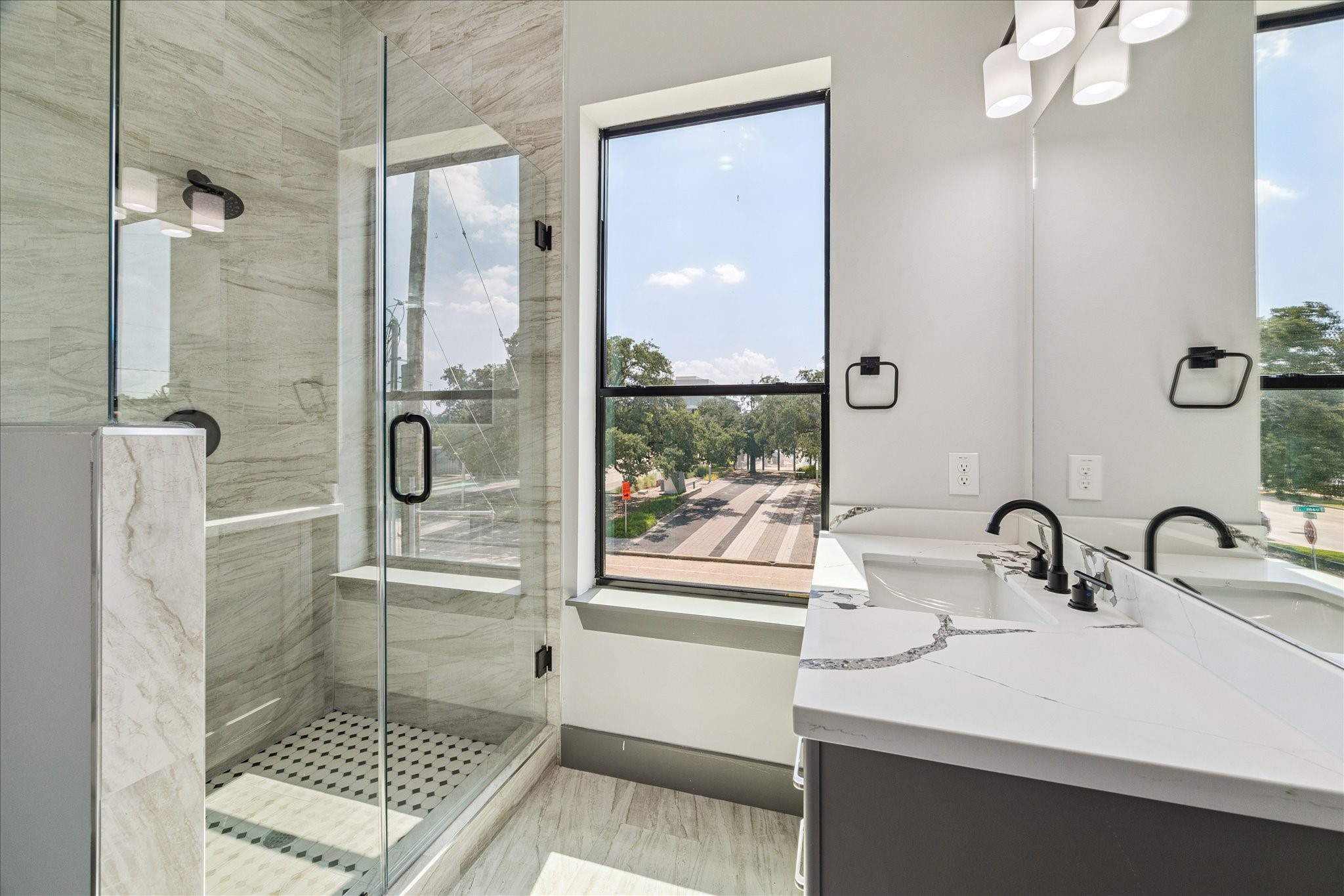 2323 Tuam Street Houston, TX 77004 - Photo 23 of 24 Glass-enclosed shower with contemporary tile and a quartz-style vanity highlight the modern design of this bathroom, while a large window adds openness and an outdoor view.