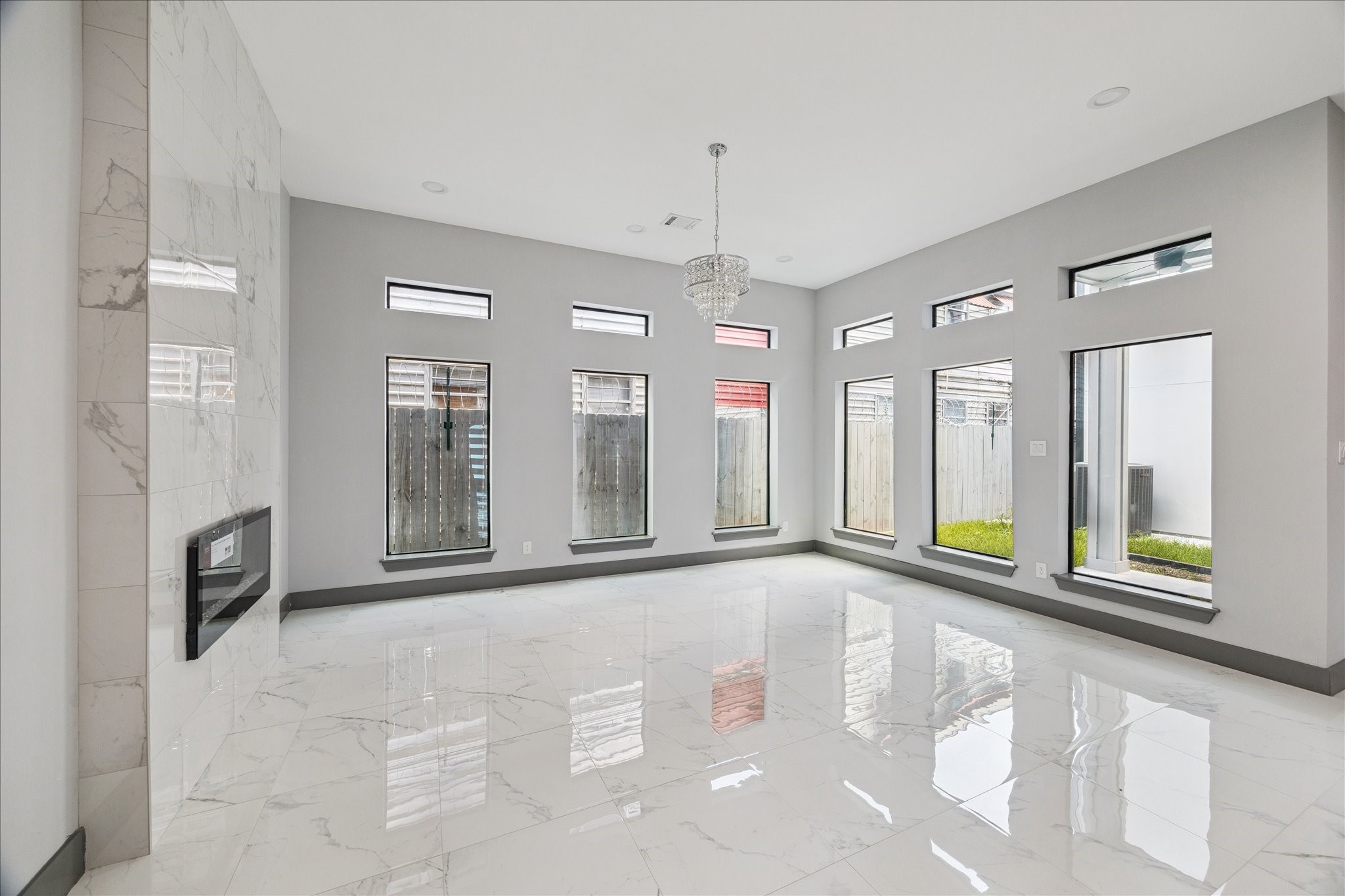 2323 Tuam Street Houston, TX 77004 - Photo 5 of 24 The living room offers an open, airy feel, with tall windows, sleek tile flooring, a standout chandelier, and a modern fireplace feature.