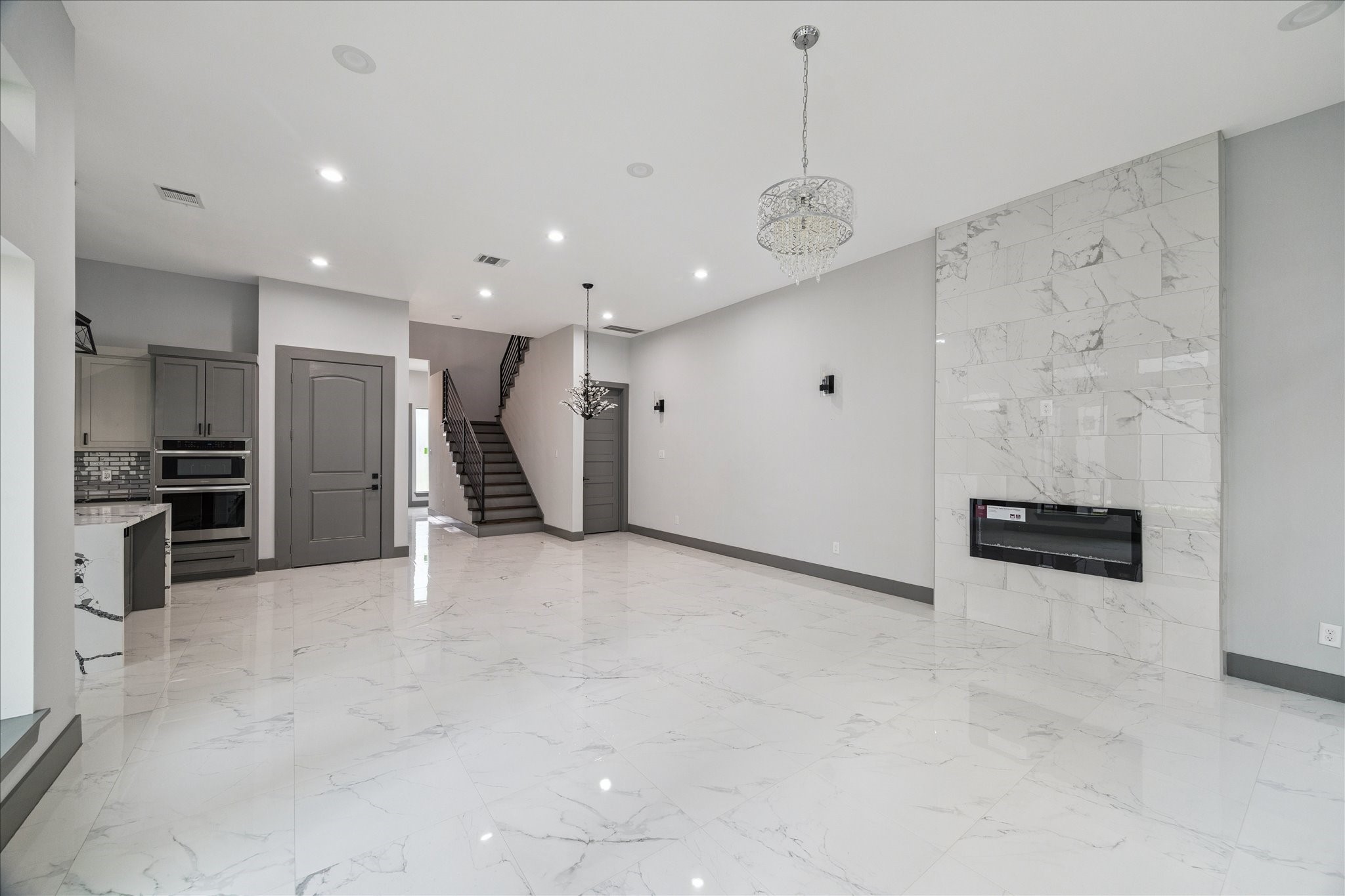 2323 Tuam Street Houston, TX 77004 - Photo 6 of 24 Expansive marble-look tile floors, a sleek modern fireplace, and elegant lighting create a sophisticated setting that flows seamlessly toward the kitchen and staircase.