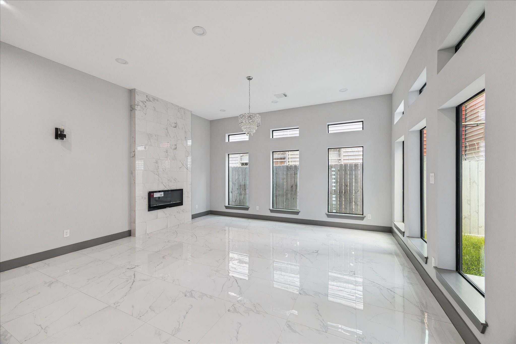 2323 Tuam Street Houston, TX 77004 - Photo 7 of 24 Polished tile floors, expansive windows, and a sleek fireplace define a bright, inviting living space suited for both entertaining and relaxing.