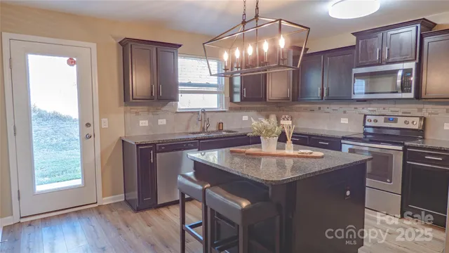 a kitchen with kitchen island granite countertop a sink cabinets and stainless steel appliances