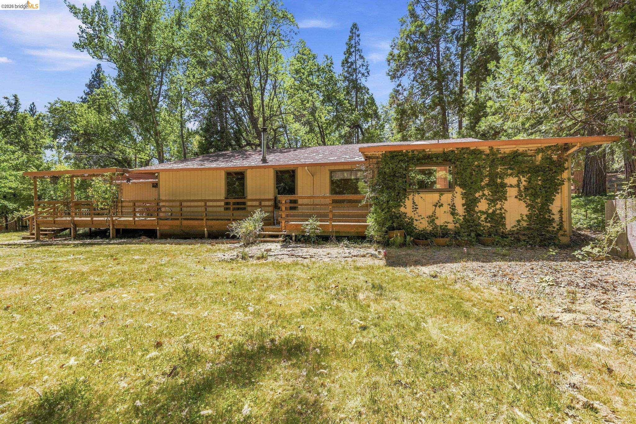 22401 South Fork Road Sonora, CA 95370 - Photo 7 of 34 Ranch-style residence featuring a full-length wooden deck, mature trees, and a separate structure with climbing greenery