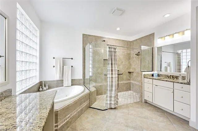 a spacious bathroom with a granite countertop tub shower and mirror