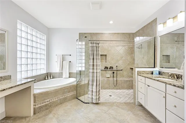 a bathroom with a double vanity sink large mirror and a bathtub