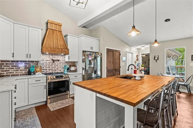 a kitchen with stainless steel appliances granite countertop a sink a stove and a refrigerator