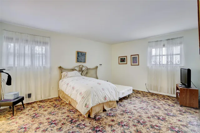 a spacious bedroom with a bed and a flat screen tv