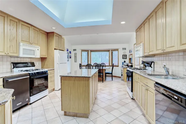 a kitchen with stainless steel appliances granite countertop a stove top oven a sink a dining table and chairs