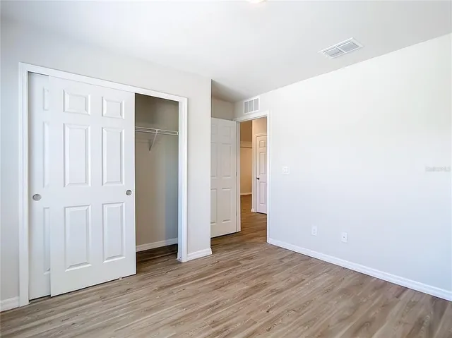 an empty room with wooden floor & closet area