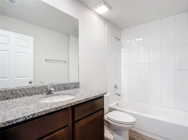 a bathroom with a granite countertop sink a toilet and bathtub