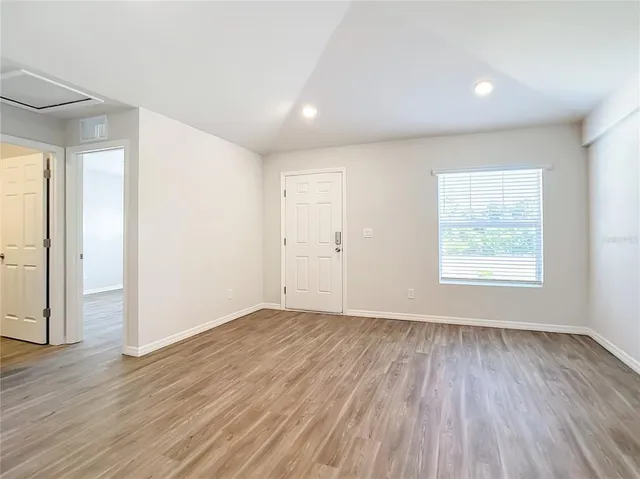 an empty room with wooden floor and windows