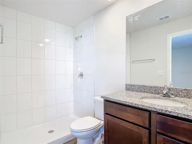a bathroom with a granite countertop sink a toilet and shower
