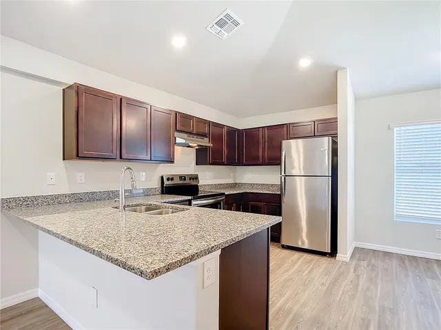a kitchen with stainless steel appliances granite countertop a sink stove and refrigerator