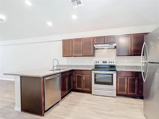 a kitchen with stainless steel appliances granite countertop a sink stove and refrigerator