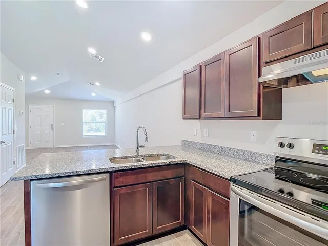 a kitchen with stainless steel appliances granite countertop a sink stove and cabinets