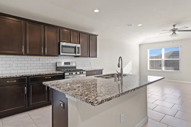 a kitchen with granite countertop a sink a stove and cabinets