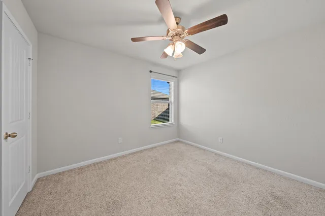 an empty room with a chandelier fan and windows