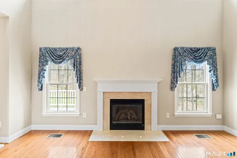 an empty room with wooden floor a fireplace and windows