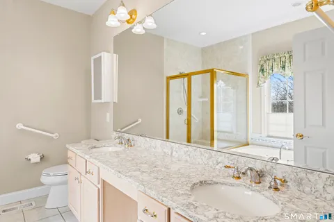 a bathroom with a granite countertop sink a large mirror and a toilet