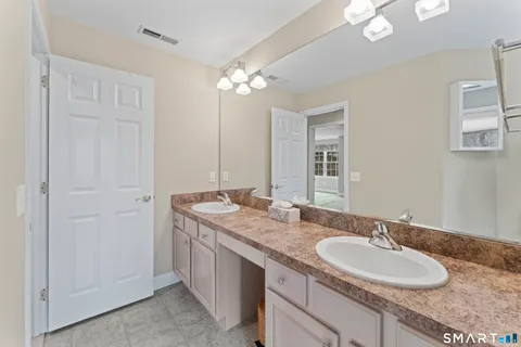 a bathroom with a granite countertop double vanity sink a mirror and a shower