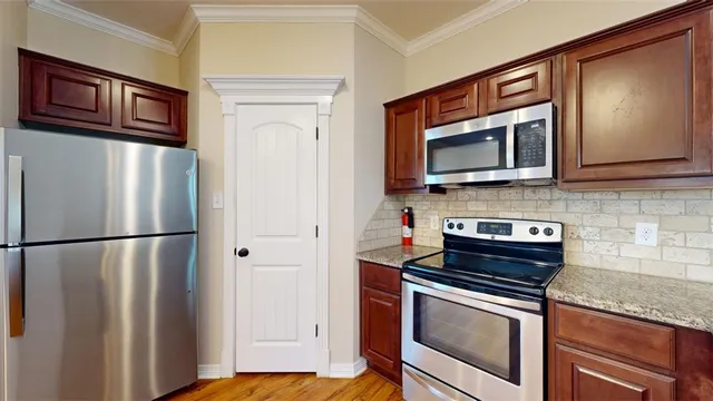 a kitchen with stainless steel appliances granite countertop wooden cabinets a microwave oven a sink and dishwasher a refrigerator with wooden floor