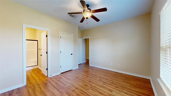 an empty room with wooden floor cabinet and windows