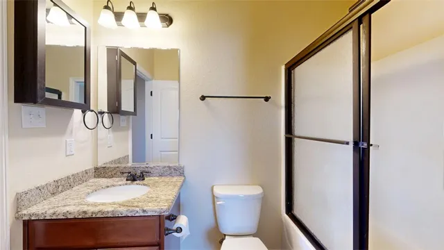 a bathroom with a granite countertop sink toilet and shower