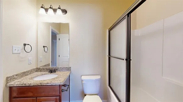 a bathroom with a granite countertop sink toilet and mirror