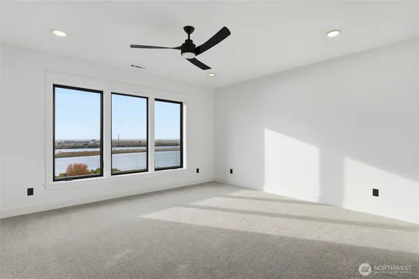 an empty room with windows and ceiling fan