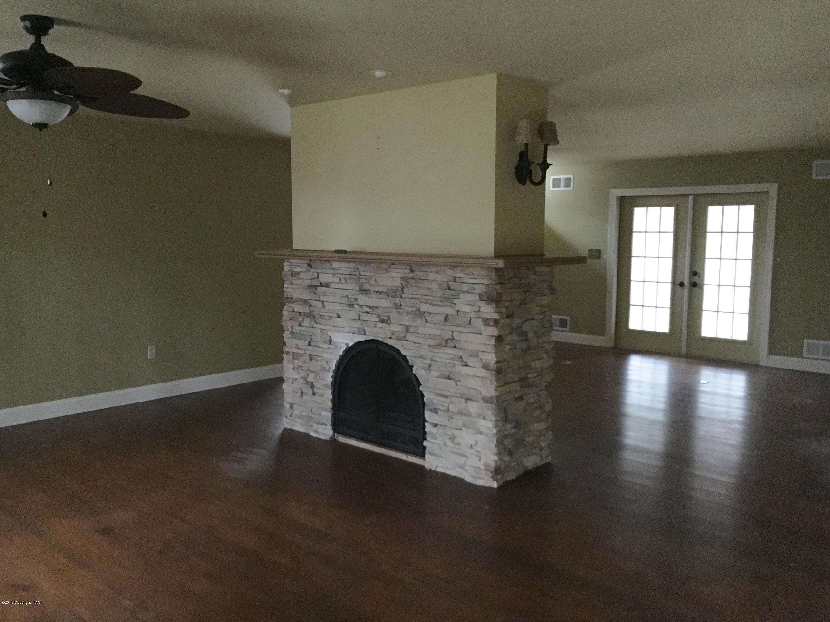 341 Ridge Circle Cresco, PA 18326 - Photo 3 of 24 an empty room with wooden floor fireplace and windows