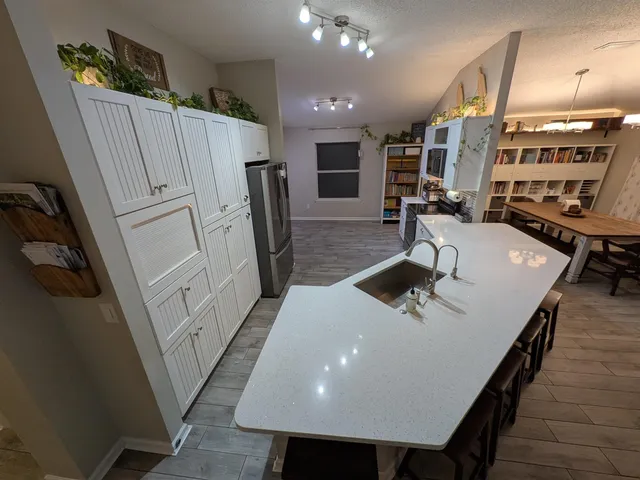 a kitchen with stainless steel appliances a table chairs in it and wooden floors
