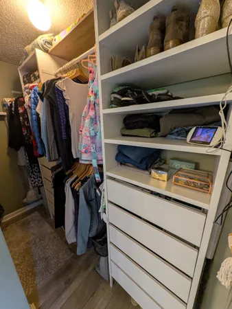 a view of walk in closet with clothes and shoes