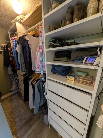 a view of walk in closet with clothes and shoes