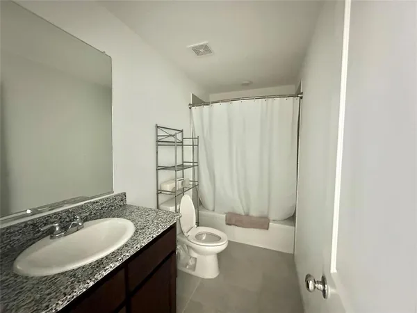 a bathroom with a granite countertop sink toilet a mirror and shower curtain