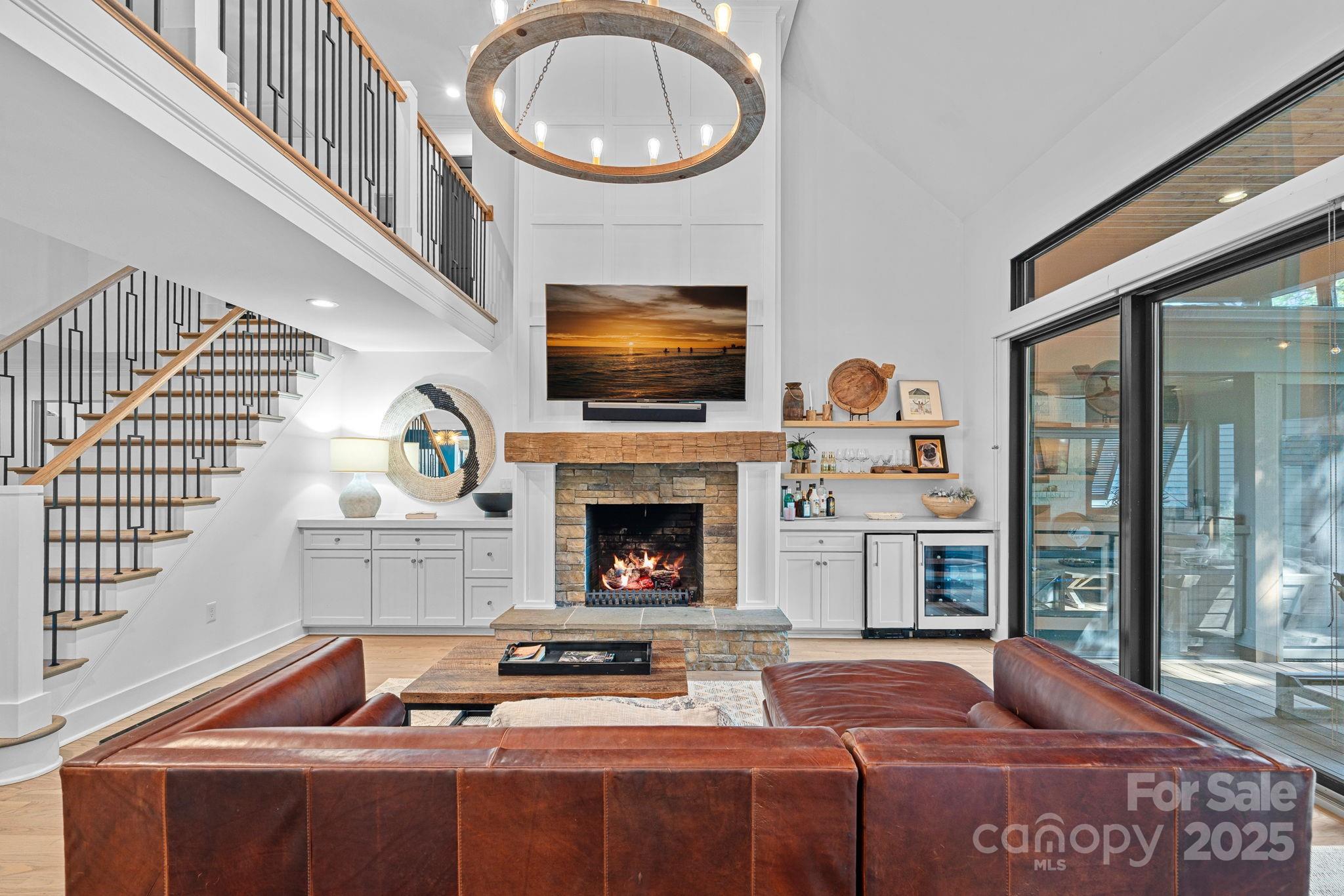 19624 Meta Road Cornelius, NC 28031 - Photo 6 of 44 a living room with a fireplace a flat screen tv and a floor to ceiling window