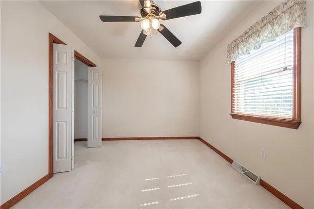 an empty room with a chandelier fan and windows
