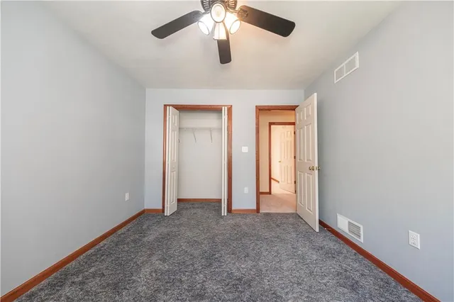 an empty room with chandelier fan and windows