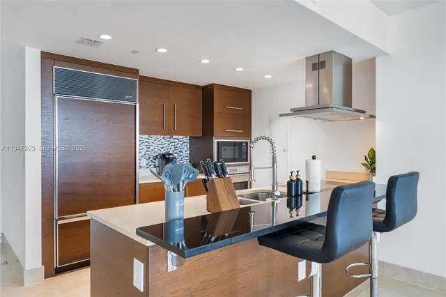 a kitchen with stainless steel appliances granite countertop a refrigerator a stove and a dining table with wooden floor