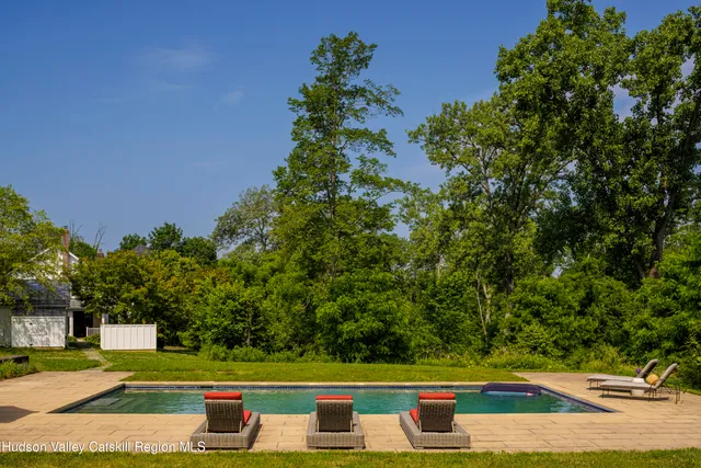 a view of swimming pool with lawn chairs and plants
