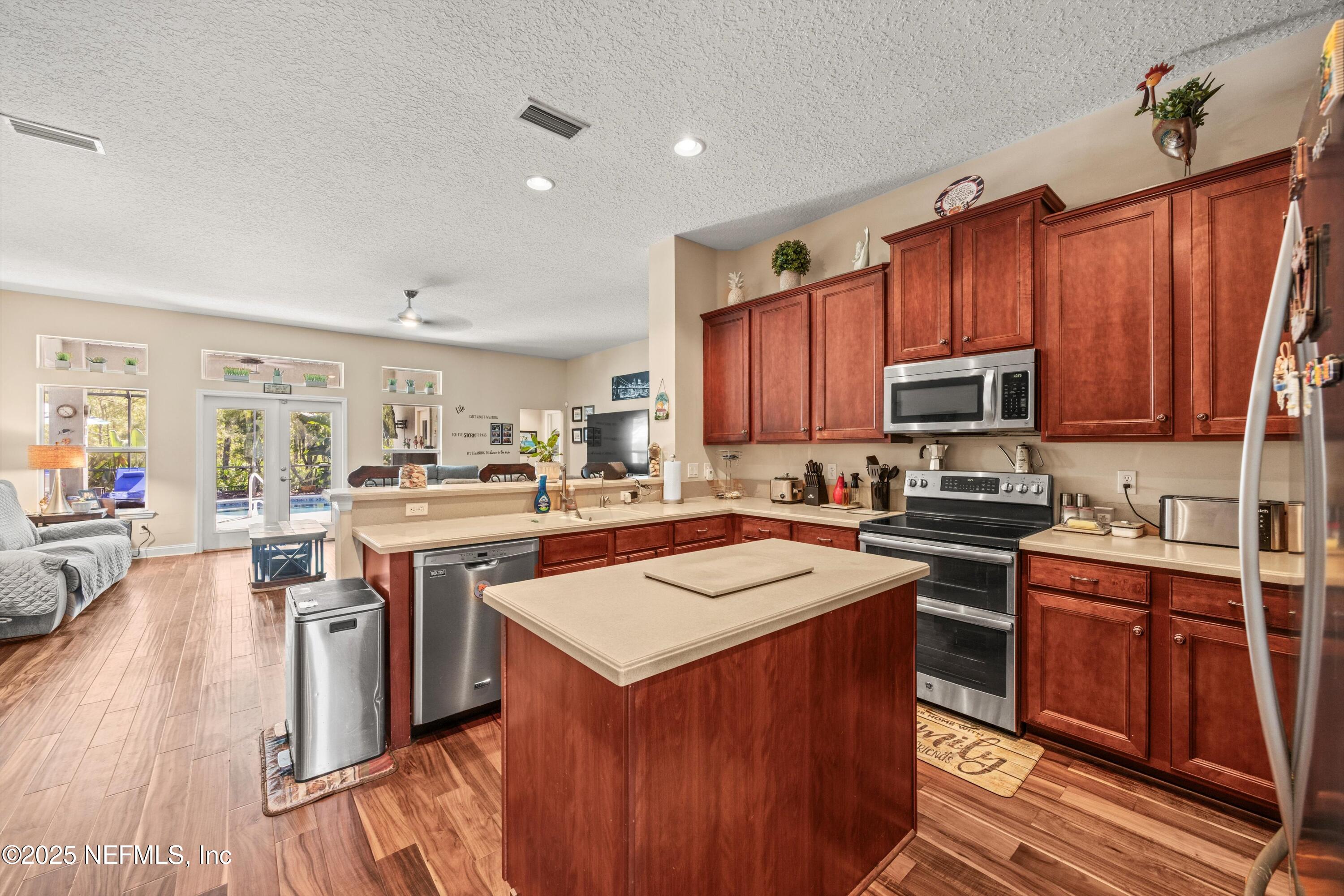 648 Battersea Drive St. Augustine, FL 32095 - Photo 20 of 59 a kitchen with stainless steel appliances granite countertop a stove top oven a sink dishwasher and a refrigerator with wooden floor
