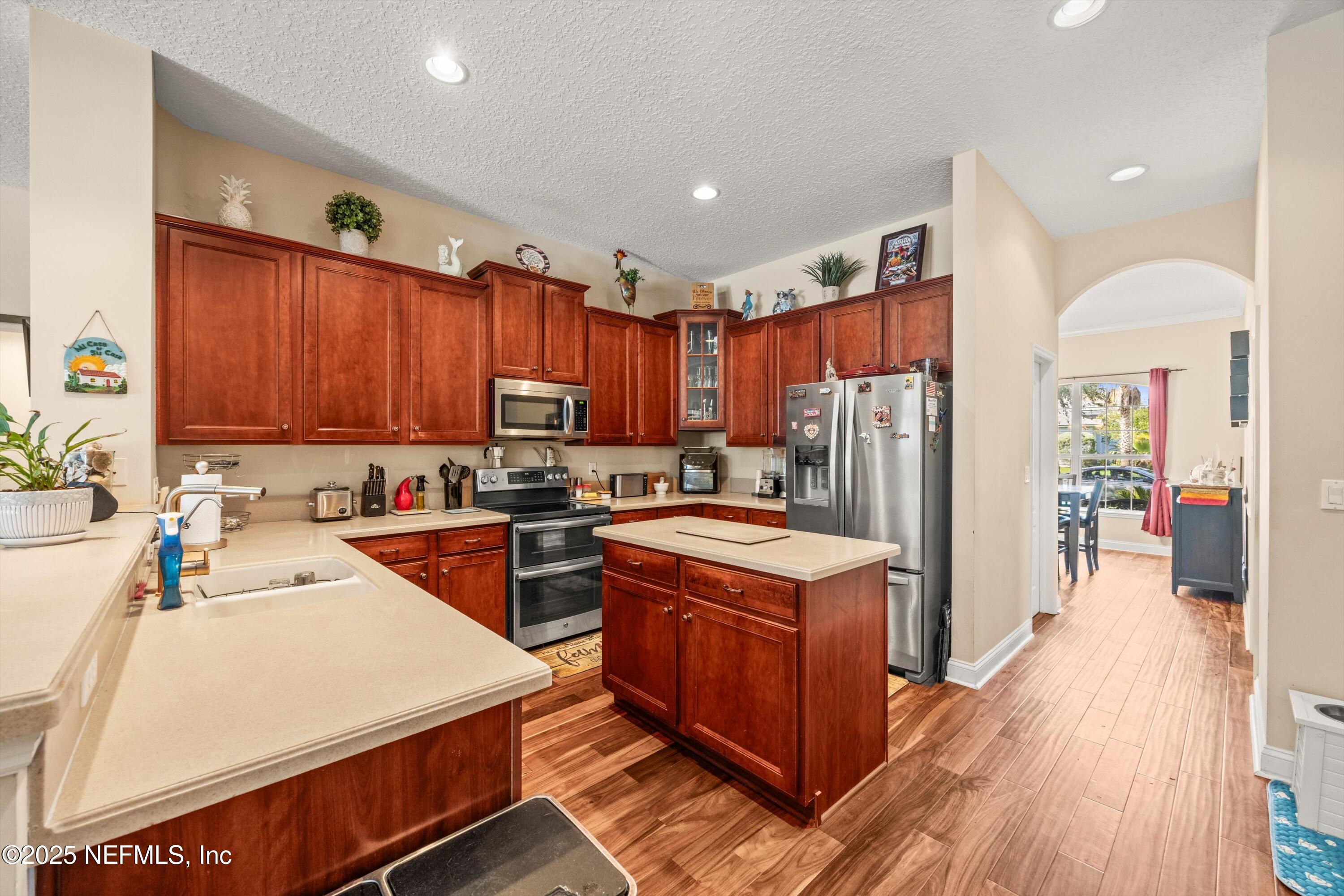 648 Battersea Drive St. Augustine, FL 32095 - Photo 23 of 59 a kitchen with stainless steel appliances sink stove refrigerator and wooden cabinets