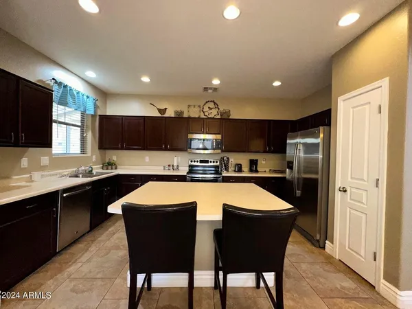 a large kitchen with kitchen island granite countertop wooden cabinets and a refrigerator