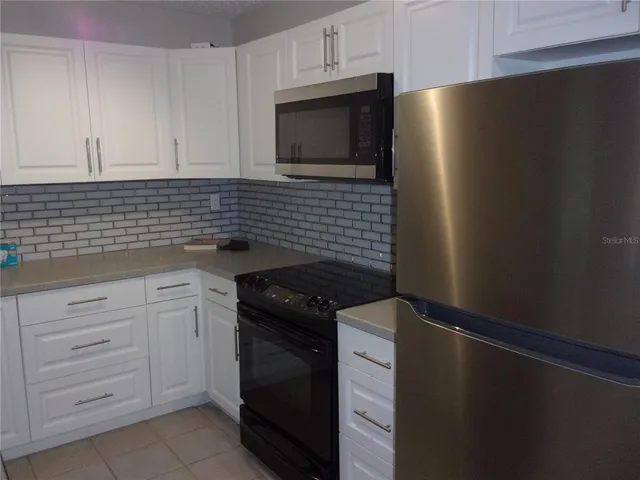 a kitchen with white cabinets and black appliances