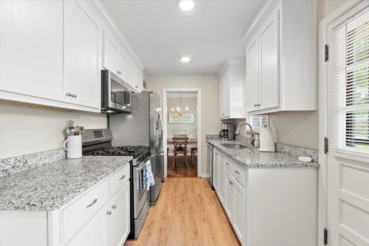 4491 Garnett Road Memphis, TN 38117 - Photo 11 of 32 Galley kitchen featuring white cabinetry, stainless steel appliances, speckled countertops, wood-finish flooring, and recessed lighting