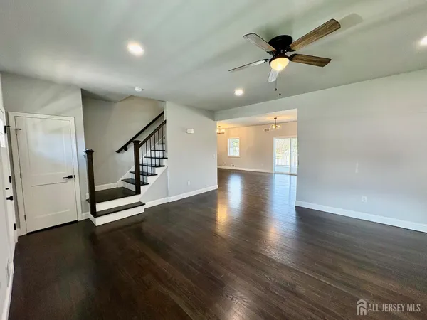 a view of an empty room with wooden floor and a ceiling fan