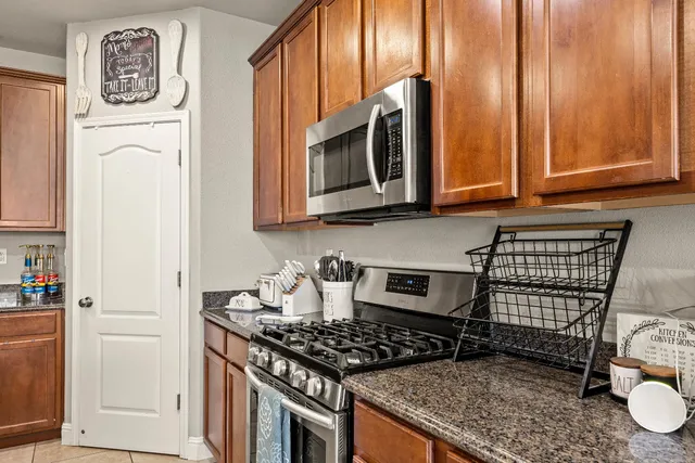 a kitchen with stainless steel appliances granite countertop a stove top oven a sink refrigerator and cabinets