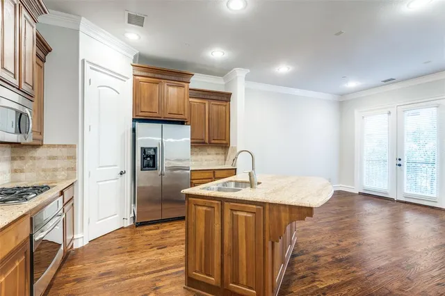 a kitchen with granite countertop kitchen island stainless steel appliances a sink stove and refrigerator