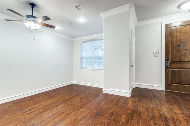 an empty room with wooden floor chandelier fan and windows