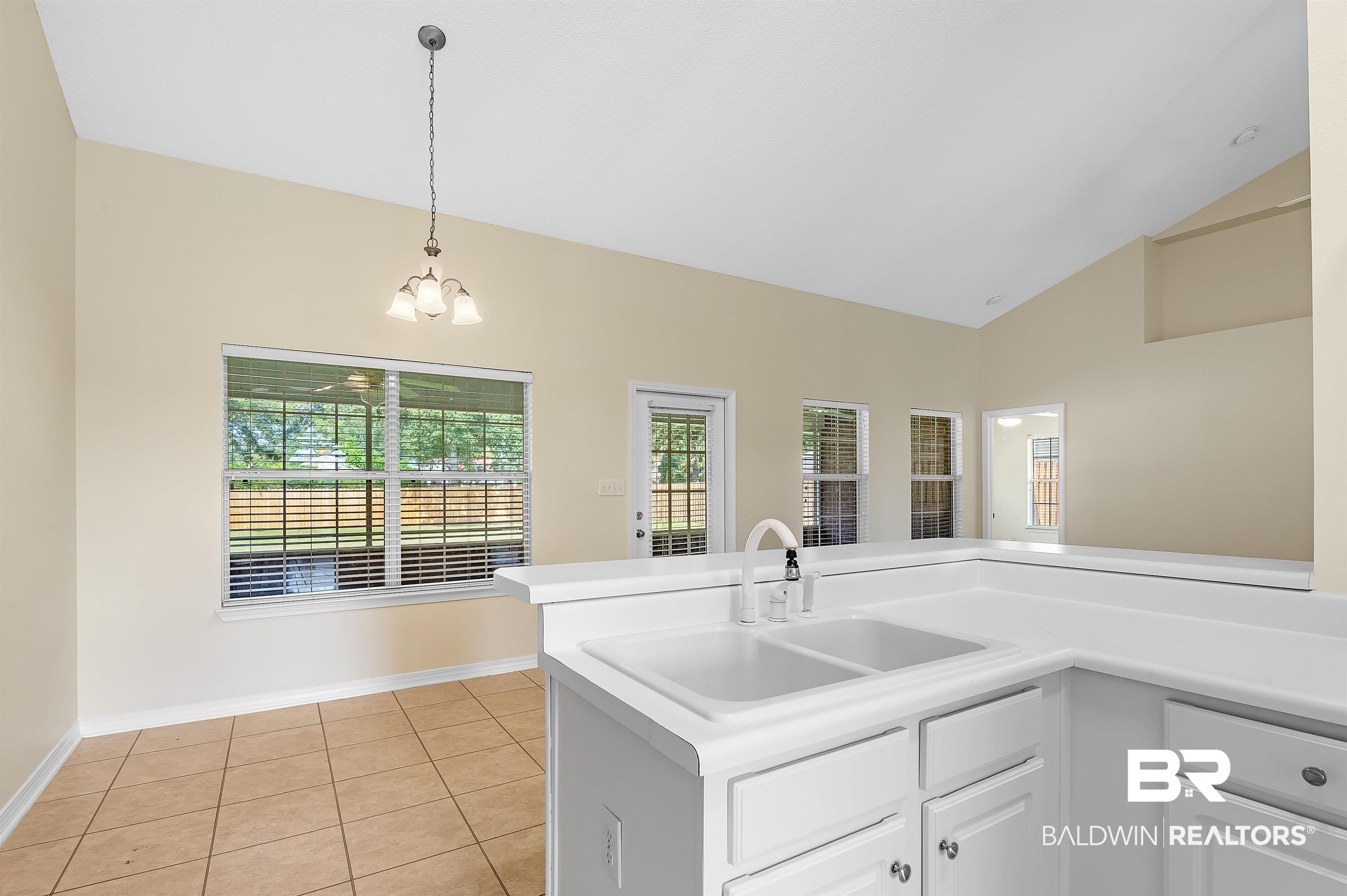 12443 Venice Boulevard Foley, AL 36535 - Photo 35 of 59 Kitchen with light tile patterned floors, vaulted ceiling, a healthy amount of sunlight, and sink